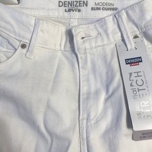 White modern slim cuffed Levi’s Denizen. Distress marks.